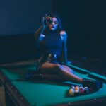 Woman Wearing Black Leather Mini Skirt Sitting on Billiard Table