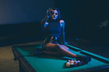 Woman Wearing Black Leather Mini Skirt Sitting on Billiard Table