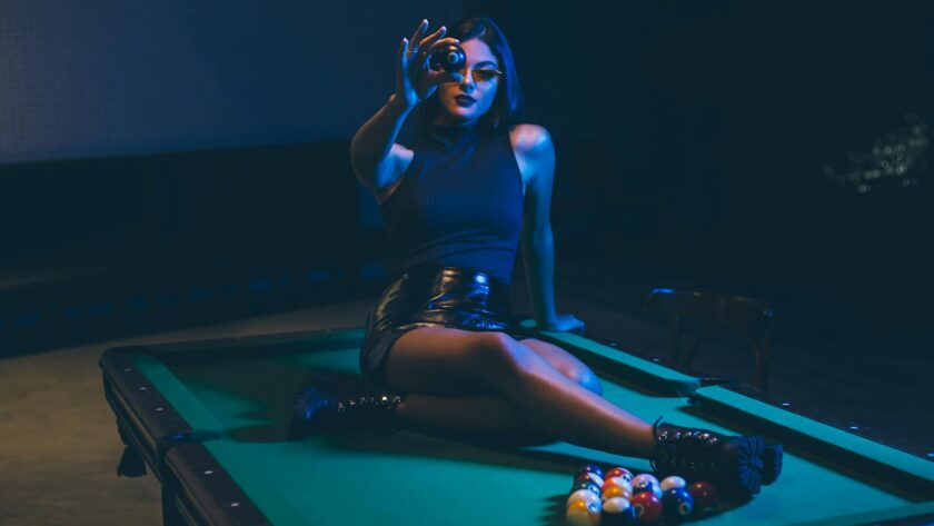 Woman Wearing Black Leather Mini Skirt Sitting on Billiard Table