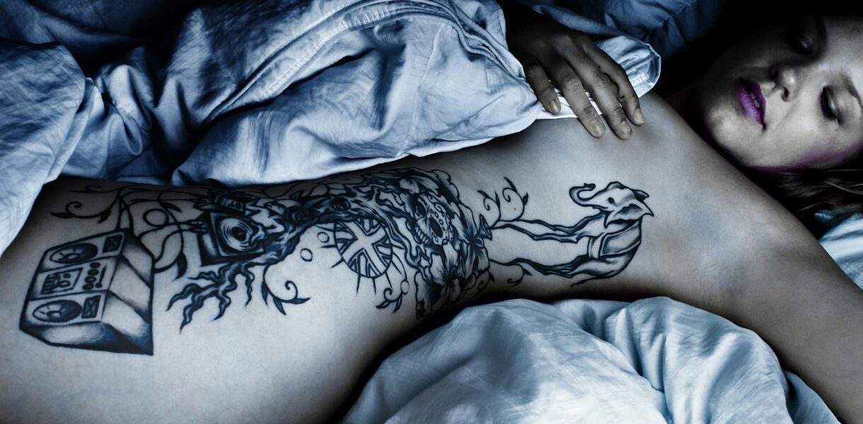 Woman with Body Tattoo Lying Down on the Bed