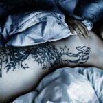 Woman with Body Tattoo Lying Down on the Bed