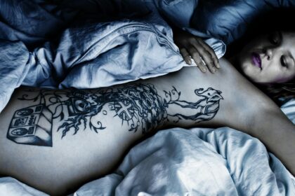 Woman with Body Tattoo Lying Down on the Bed