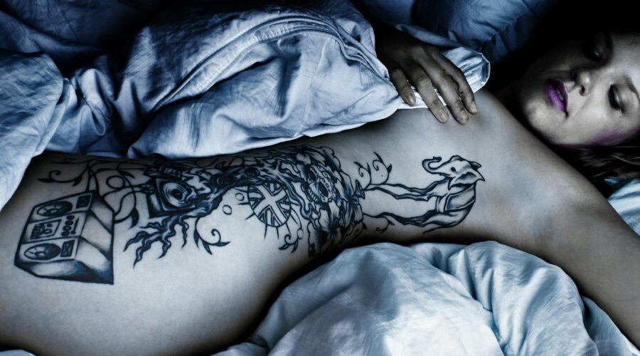 Woman with Body Tattoo Lying Down on the Bed